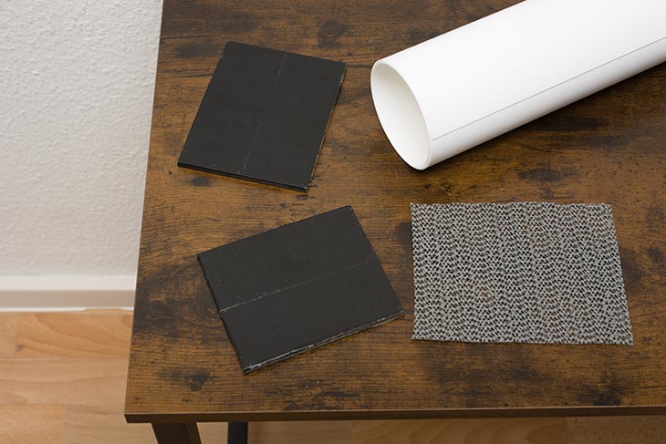 Material für Tabletop-Aufnahmen: Kunststoff-Hohlkehle, Gummimatte und Gewichte liegen auf einem Tisch.